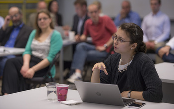 A woman in a classroom of students asks a question